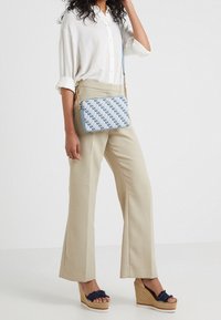 Borsa a tracolla con un design a fantasia blu chiaro che presenta le lettere "MK". Cinturino a catena regolabile. Forma rettangolare piatta.