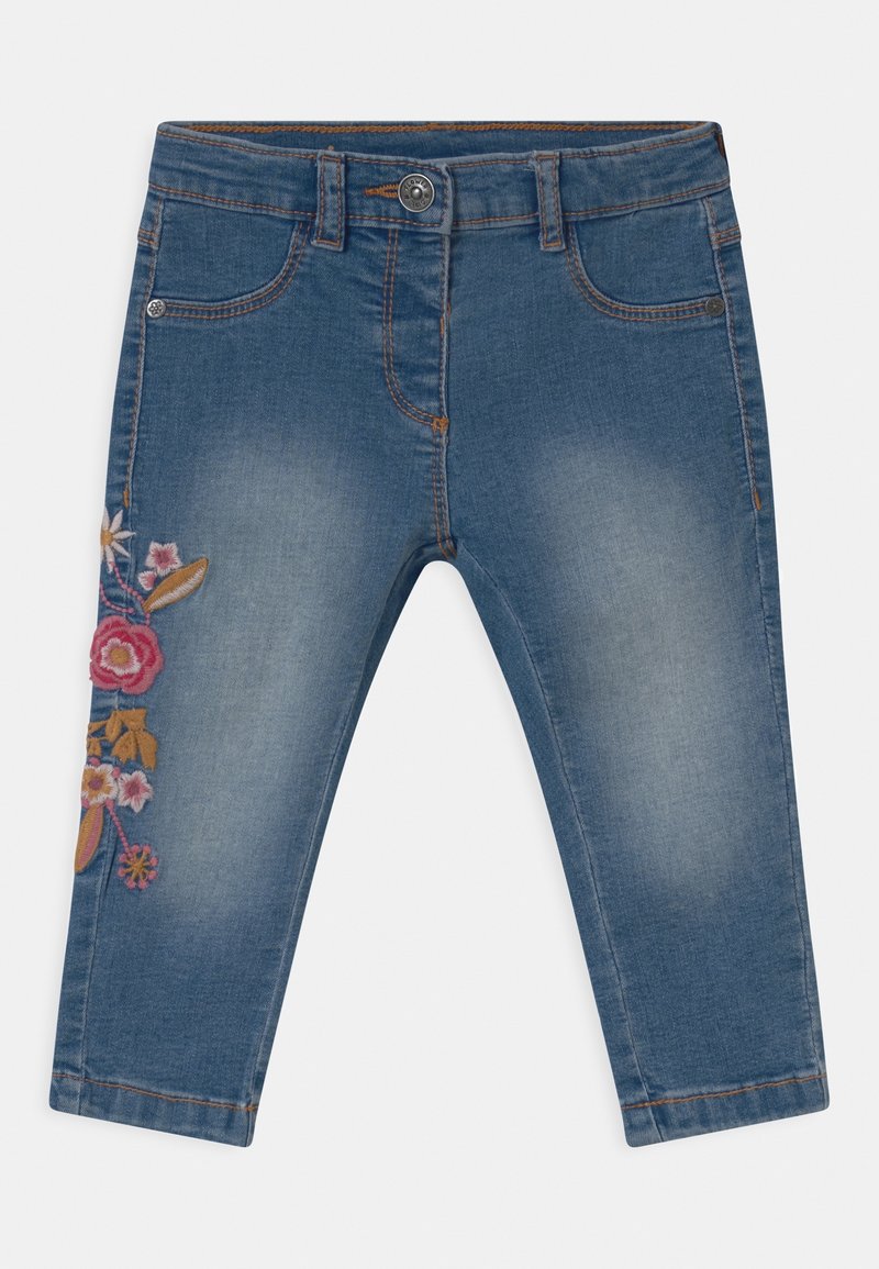 Pantaloni capri in denim azzurro chiaro con finitura sbiadita. Presentano un ricamo floreale in rosa, arancione e giallo sulla gamba sinistra.
