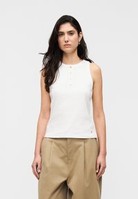 Λευκό αμάνικο τοπ από βαμβάκι με στρογγυλή λαιμόκοψη, που διαθέτει πέντε κουμπιά σε χρυσό τόνο και ένα μικρό λογότυπο στο τελείωμα.