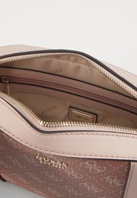 Brązowa i beżowa torebka z złotymi zamkami błyskawicznymi, teksturowaną powierzchnią z wzorem logo oraz różową podszewką wewnątrz. Widoczne liczne przegródki.