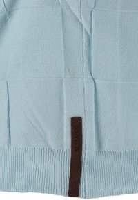 Jasnoniebieski, dziany sweter z teksturowanym wzorem w kratę oraz brązową skórzaną metką z napisem "KEY LARGO" na dolnym brzegu.