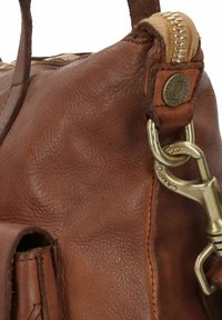 Sac à main en cuir marron avec une finition texturée, une fermeture éclair dorée et des accessoires en métal. Comprend un clip pour attacher à d'autres objets.