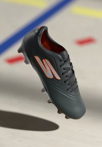 Black football boot with a smooth texture, featuring orange accents, a rounded toe, and six cleats on the sole for traction.