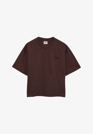 Brun bomulds t-shirt med korte ærmer, rund hals og et lille broderet logo på venstre side. Boxy pasform med en glat tekstur.