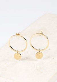 Goldene Creolen mit polierter Oberfläche, die unten eine hängende kreisförmige Scheibe haben. Leichtes und schlankes Design.