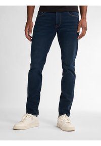 Tmavě modré džíny slim fit s předními kapsami, jemnými detaily whiskering a kombinované s krémovými teniskami.