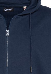 Felpa con cappuccio blu navy con zip, realizzata in tessuto morbido, con cerniera metallica e cordini, con una piccola etichetta del marchio sul colletto interno.