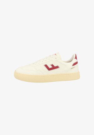 White leather sneaker with red logo detailing, textured cream rubber sole, and lace-up closure. Features minimalist design and contrasting accents.