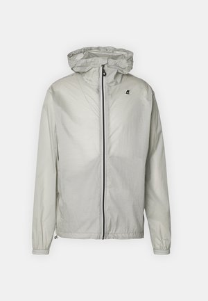 Hellgraue Kapuzen-Windjacke mit durchgehendem Frontreißverschluss und elastischen Bündchen, mit kleinem schwarz-weißem Logo auf der Brust.