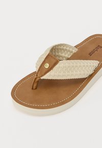Sandale din piele maronie cu o curea țesută de culoare bej, având un accent auriu și cusături albe pe talpă. Design neted și plat.