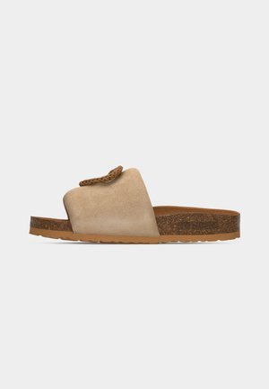 Beige suède slip-on sandaal met gevlochten banddetail, kurken voetbed en lichtbruine rubberen zool, zijaanzicht op een neutrale achtergrond.