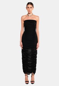 Zwarte strapless jurk met verzamelde ruches, aansluitende vorm en doorschijnende panelen aan de zoom. Draag met zwarte enkelsandaaltjes.