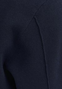 Tessuto di un blu navy texturizzato, con una superficie liscia e cuciture visibili. Il materiale sembra morbido e flessibile, con leggere variazioni di tonalità.