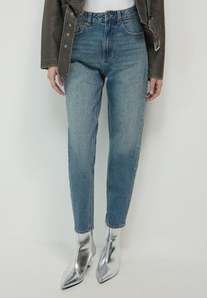 Jeans in denim blu a vita alta con una leggera scoloritura, design a gamba dritta, completati da stivaletti argentati a punta.