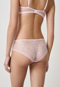 Set di lingerie in pizzo rosa chiaro, con un motivo floreale, bordi ondulati sulla cintura e spalline regolabili sul reggiseno.