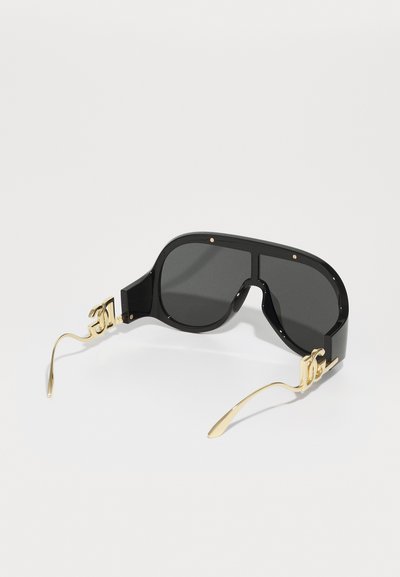 Schwarze übergroße Sonnenbrille mit eckigen Gläsern, goldenen Akzenten an den Schläfen und glattem, glänzendem Finish. Dunkle Gläser bieten Sonnenschutz.