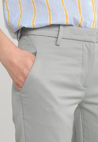 Grijze broek met een gedessineerde stof. Heeft een slim fit, zijzakken en een soepele tailleband. Gemaakt in combinatie met een gestreept shirt in meerdere kleuren.