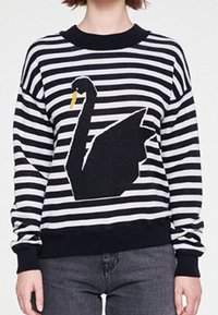 Sweter w czarno-białe paski z dużym wzorem czarnej łabędzi z żółtym dziobem. Ma okrągły dekolt i ściągacze przy mankietach.