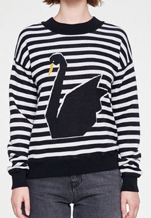 Pull en rayures noires et blanches avec un grand motif de cygne noir présentant un bec jaune. Il a un col rond et des poignets côtelés.