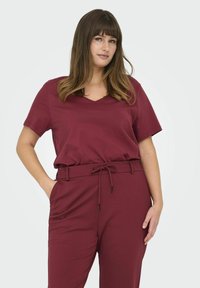 Bordeaux top met een v-hals en korte mouwen, gecombineerd met bijpassende broek met een elastische tailleband en trekkoorddetail.