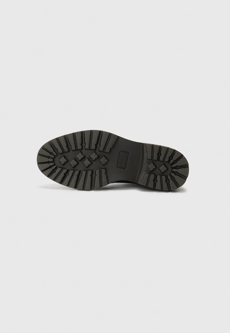 Suola di scarpa in gomma nera con un motivo di battistrada testurizzato che presenta forme rettangolari e a diamante per una migliore aderenza. Design piatto e spesso per garantire durata.