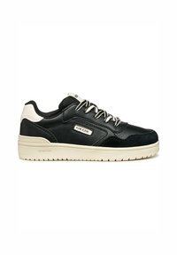 Baskets en cuir noir avec des accents en daim, présentant une semelle en caoutchouc crème, des œillets en métal et une étiquette de marque sur le côté.