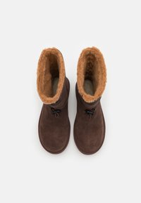 Bottines en daim marron avec doublure en fourrure chaude couleur tan et fermetures à bascule, vues de dessus sur fond blanc.