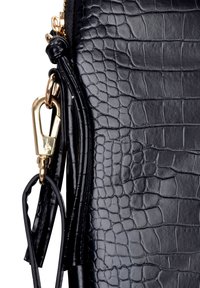 Zwarte neplederen tas met krokodillenstructuur, voorzien van goudkleurige hardware, een ritssluiting en een afneembare riem met kwastaccenten.