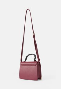 Borsa a mano in pelle sintetica color bordeaux con una forma strutturata, un manico attorcigliato in bianco e nero e una tracolla removibile.