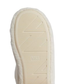 Suela de zapatilla de color crema con una superficie de goma texturizada, que presenta patrones horizontales y en zigzag; bordeada de un material suave y esponjoso.