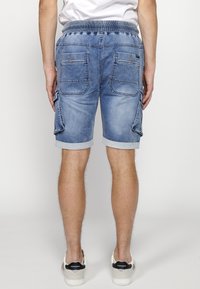 Lysblå denimshorts med en falmet finish, der har en strækbar talje, oplagte opkrøllede kantlinjer og flere lommer med lynlåsdetaljer.