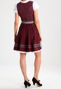 Robe bordeaux avec un corsage ajusté, une jupe évasée et une bordure en dentelle blanche. Comprend un haut texturé, des accents argentés et des talons noirs.