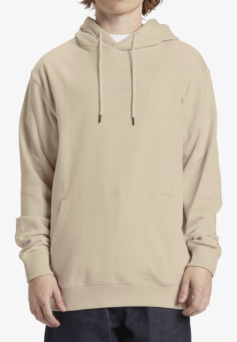 Felpa beige con cappuccio, dotata di tasca frontale, cordini e un logo discreto sul petto; tessuto morbido e vestibilità rilassata.