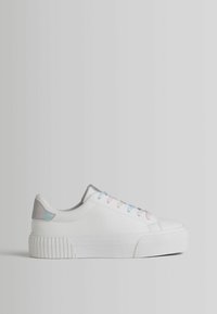 White sneaker with a textured rubber sole, accented by iridescent heel and pastel-colored laces in pink and blue. Smooth leather upper.