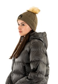 Giubbotto puffer grigio scuro con finitura lucida e cappuccio removibile, abbinato a un berretto a coste verde oliva con pompon e patch con logo.