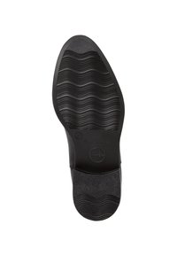 Suela de zapato negra con un patrón de banda de rodadura ondulada, presentando un borde superior suave y texturizado y un logo circular grabado cerca del talón.