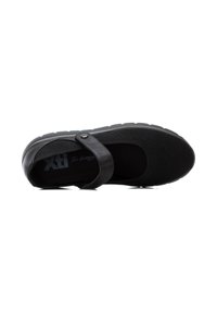Zapato negro tipo slip-on con parte superior de tela y punta texturizada. Presenta una suela de goma plana y una correa con un detalle de botón plateado.