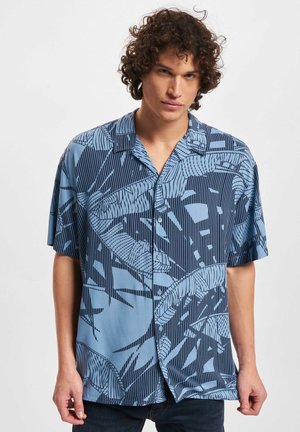 Chemise bleue à manches courtes avec un motif de feuilles. Fabriquée en tissu léger, elle possède des boutons et un col. Détails subtils en rayures verticales.