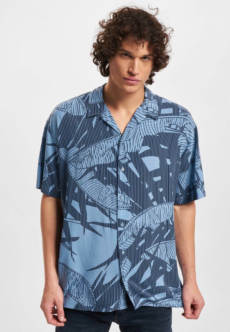 Camicia azzurra a maniche corte con un motivo a foglia. Realizzata in tessuto leggero, presenta bottoni e colletto. Dettagli a righe verticali sottili.