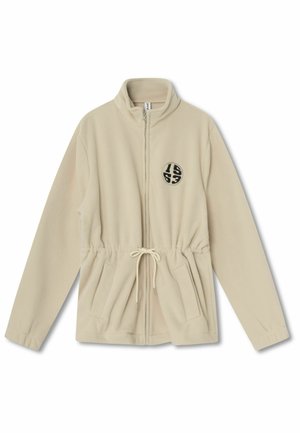 Beige Fleece-Zip-Jacke mit hohem Kragen, verstellbarem Kordelzug in der Taille, zwei Fronttaschen und einem runden schwarzen Logo auf der linken Seite.