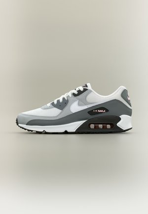 Nike Air Max tenisica u bijeloj, sivoj i crnoj boji s vidljivim zračnim jastučićem i ružičastim natpisom "Air Max" sa strane potplata.