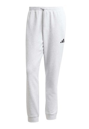 Pantalones deportivos gris claro con cintura elástica y cordón, piernas ajustadas, puños en los tobillos y un pequeño logo negro de Adidas en la parte superior del muslo izquierdo.