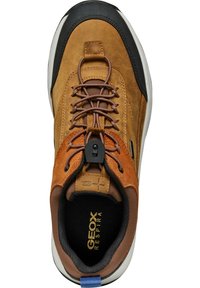 Zapatilla de cuero marrón y ante con una puntera de goma negra, cordones texturizados y una lengüeta en el talón de color azul contrastante. Presenta un diseño transpirable.