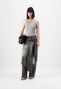 Sivý rebrovaný tielko, skombinované s voľnými sivými džínsami s viazaním v páse. Modelka drží čiernu koženú clutch kabelku. Biele pozadie.