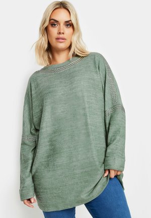 Olivegrüner, übergroßer Pullover aus weichem Stoff mit einem Bootsausschnitt und dekorativen metallischen Nieten entlang der Schultern und Ärmel.