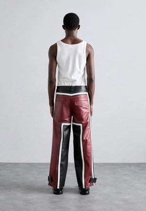 Red and black leather trousers with white accents, wide-legged design, side hardware details, and a black waistband with logo.