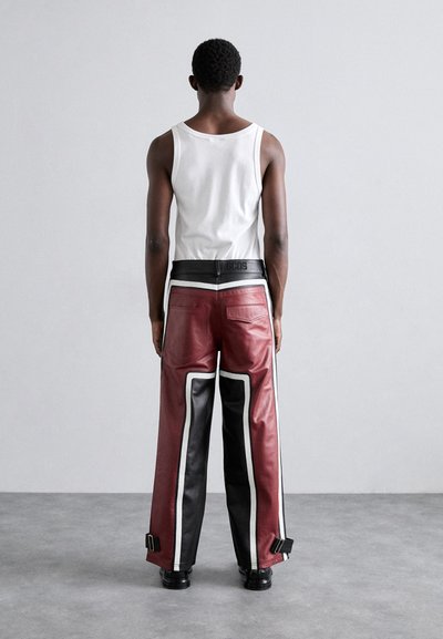 Pantaloni in pelle rossi e neri con dettagli bianchi, design a gamba larga, particolari hardware laterali e una vita nera con logo.