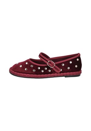Zapato plano de ante color burdeos con tachuelas plateadas, una correa con hebilla y una suela trenzada, mostrado de perfil sobre un fondo blanco.