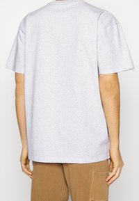 Lysegrå bomulds t-shirt med rund halsudskæring, korte ærmer og løs pasform. Bagsiden er ensfarvet uden synlige logoer eller design.
