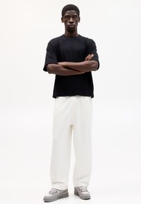 Czarny, oversize t-shirt, białe, dopasowane spodnie, szare sneakersy. Gładka tekstura, krótkie rękawy, luźny krój, prosty design.